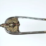 Hrobová výbava velmože z Blučiny. Muž byl vybaven dlouhým dvojbřitým mečem (spathou) Nákončí pochvy dlouhého dvoubřitého meče – spathy vyrobené z pozlaceného stříbra a zdobené technikou nielo a šesti almandinovými vložkami (doba stěhování národů, 450 – 480 n. l.).